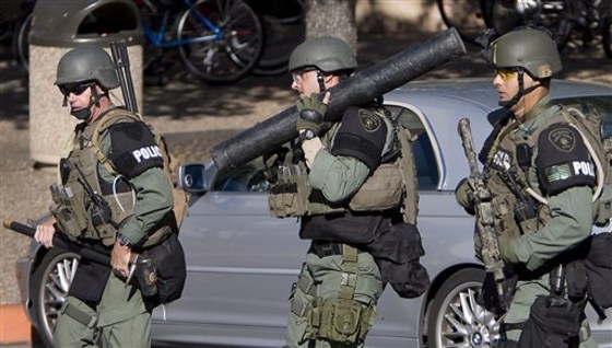 Austin law enforcement officials, one holding a battering ram, center, head out to buildings surrounding the Perry-Castaneda Library on the University of Texas campus on Tuesday, when a man wearing a ski mask opened fire with an AK-47 inside a library, then fatally shot himself, police said.